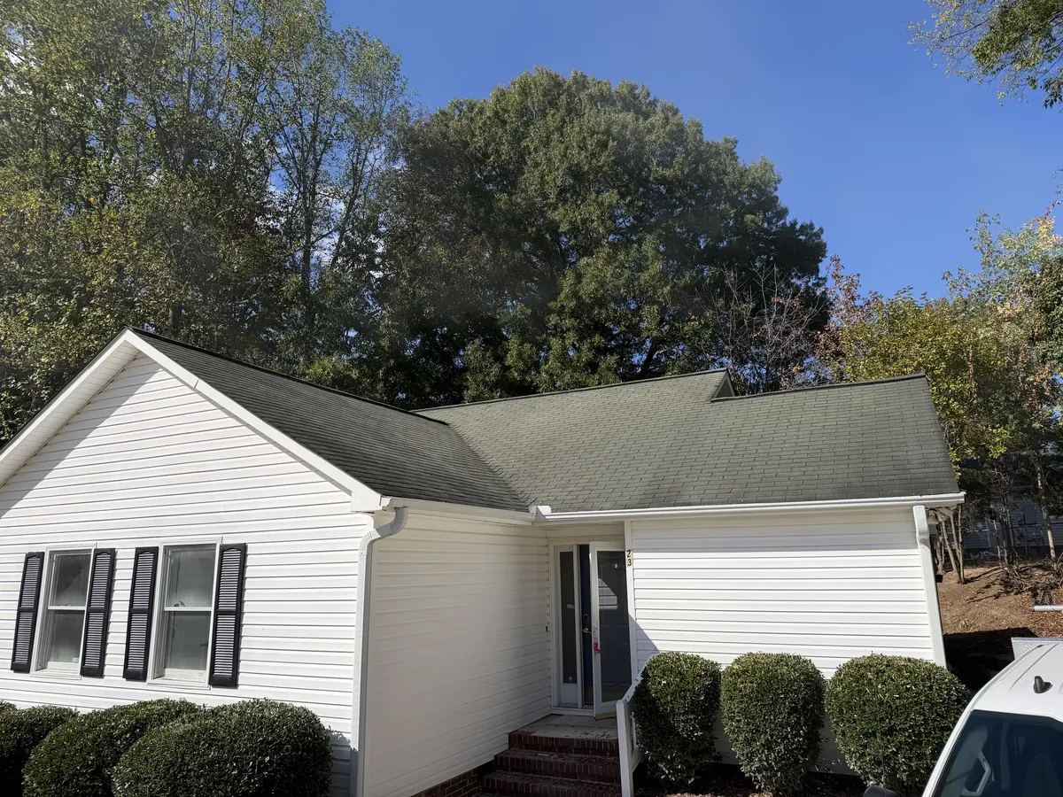 A white vinyl-sided ranch home with an aging asphalt shingle roof in North Carolina